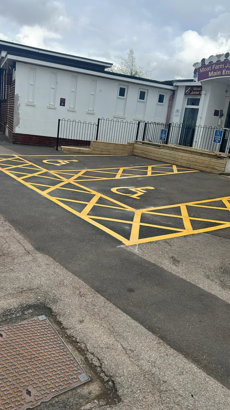 Numbered disabled parking bays with wheelchair symbols and yellow access hatching at a commercial building