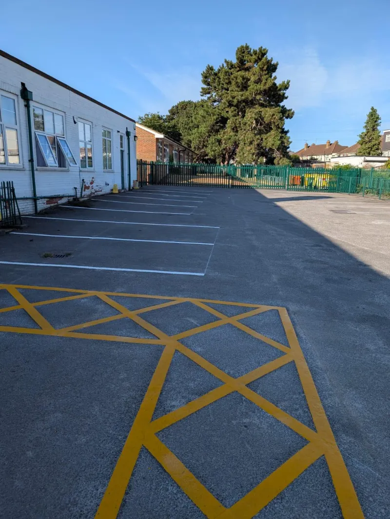 White parking bays and a yellow keep-clear hatched zone marked alongside a building