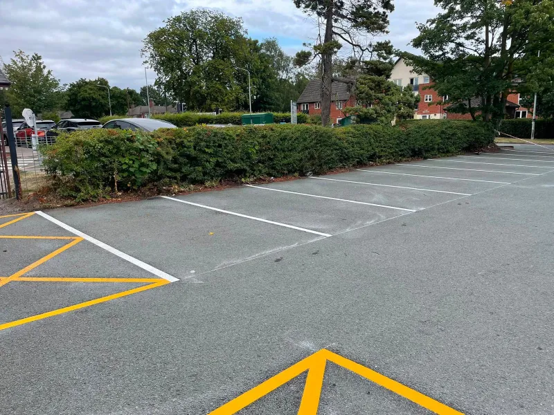 Crisp white parking bay lines with yellow chevron hatching on a resurfaced car park