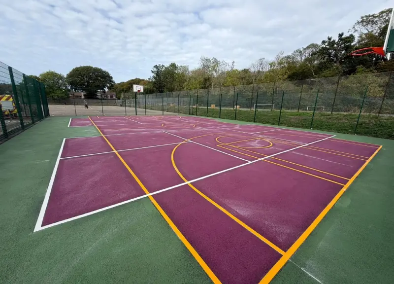 A full-colour coated MUGA surface in purple with yellow and white court lines