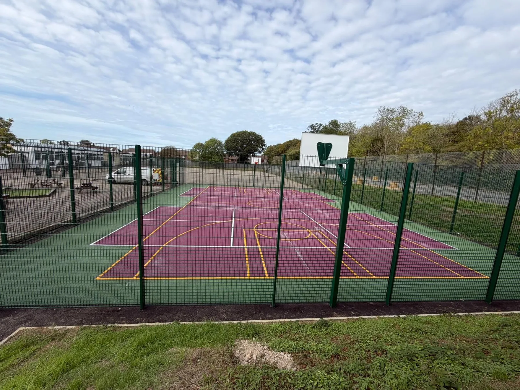 Purple MUGA surfacing with a basketball hoop and netball court lines