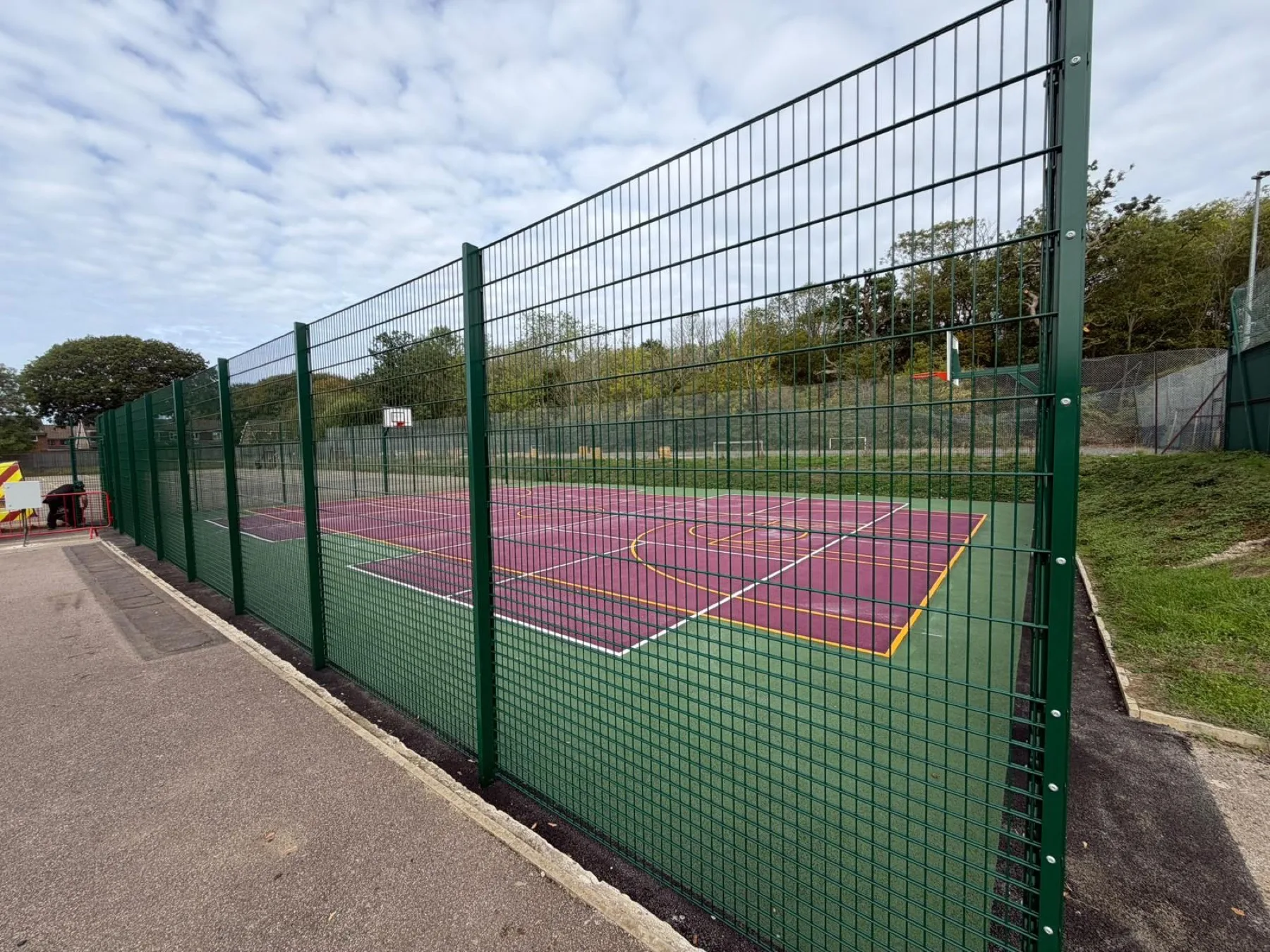 Fenced coloured MUGA with multi-sport court markings at a school